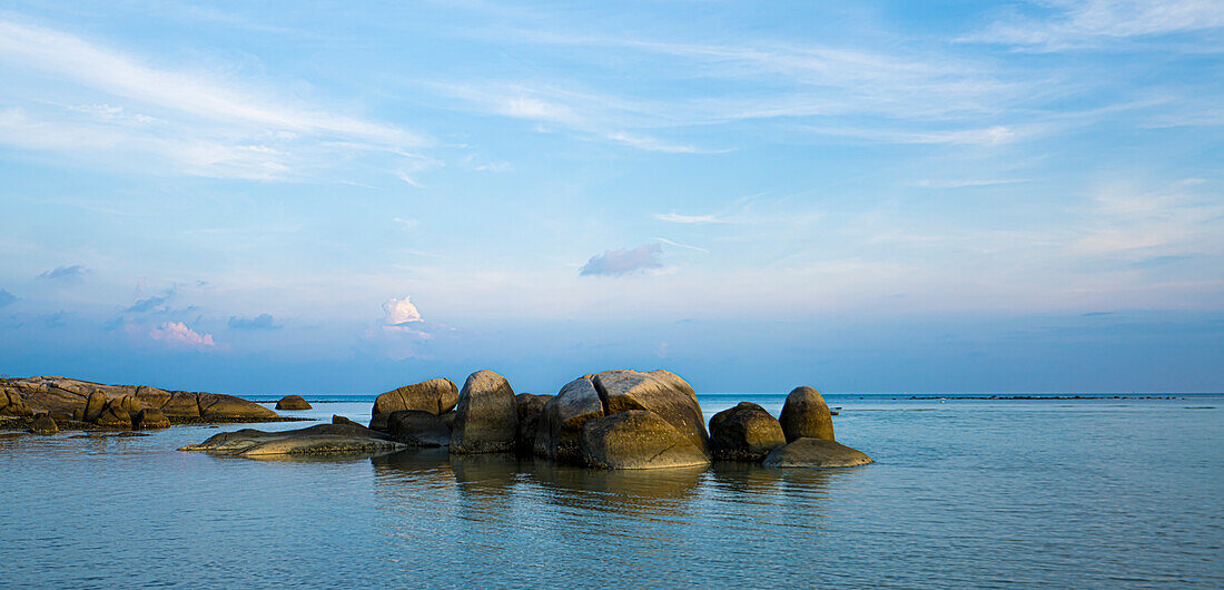 Dawn over a lagoon with rock formations along the shore of the calm, waters on the coast of Ko Samui Island in the Gulf of Thailand; Ko Samui, Surat Thani, Thailand