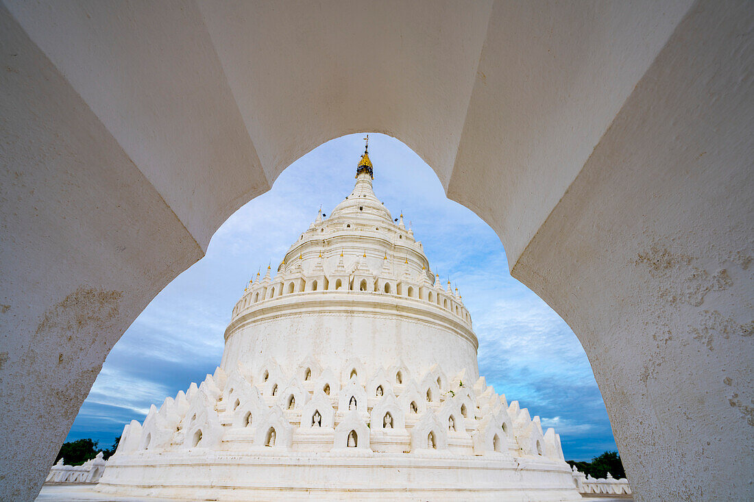 View through the entrance archway of the Hsinphyume Pagoda (Mya Thein Tan Pagoda) painted white with its design based on the Buddhist sacred mountain of Mount Meru, situated on the western bank of the Ayeyarwady (Irrawaddy) River; Mingun, Sagaing Region, Myanmar (Burma)