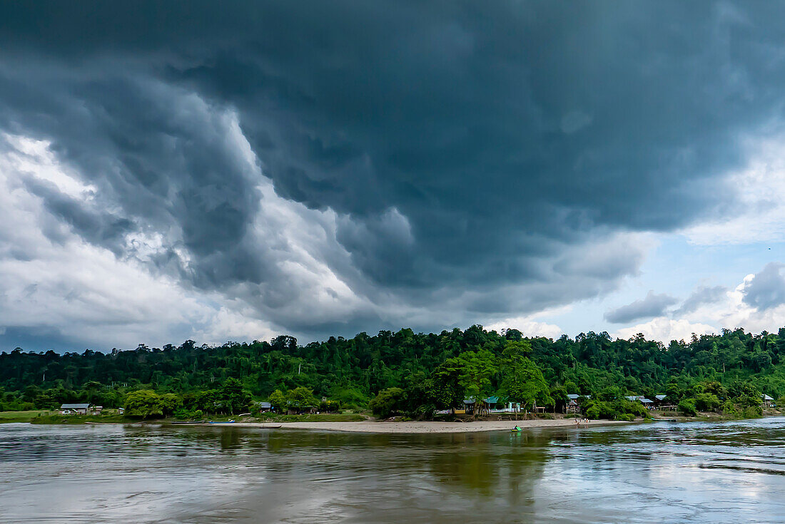Gewitterwolken bilden sich über dem Dorf am Ufer des Ayeyarwady (Irrawaddy); ländlicher Dschungel, Kachin, Myanmar (Birma)