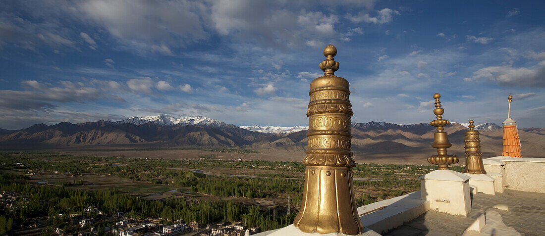 Blick vom Dach des Klosters Thikse mit seinen großen goldenen Säulen, über das Dorf und das Indus-Tal, durch die Himalaya-Berge von Ladakh, Jammu und Kaschmir; Thiksey, Ladakh, Indien.
