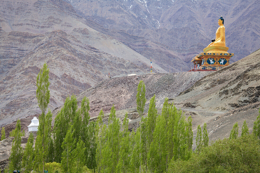 Riesige vergoldete Statue eines sitzenden Buddhas (2012 geschaffen) im Stok-Tal auf einem Berggipfel, der über das Stok-Kloster und das Dorf in den Himalaya-Bergen von Ladakh, Jammu und Kaschmir wacht; Stok, Ladakh, Indien