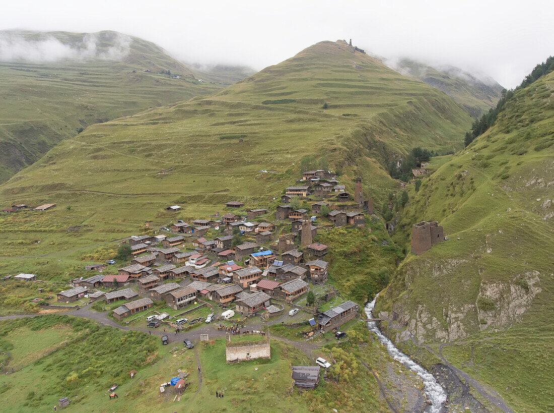 Aerial view of the mountainside village of Dartlo and its ruins of medieval towers with the Kvavlo Tower on the mountaintop in the distance in Tusheti National Park; Dartlo, Kakheti, Georgia