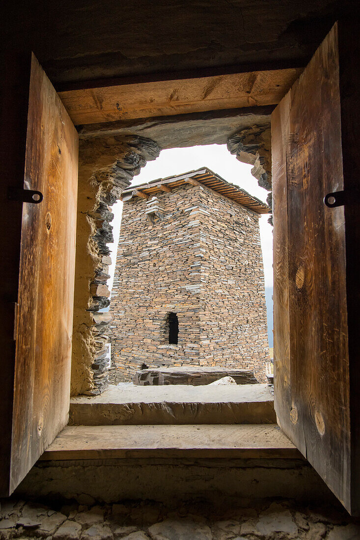 Nahaufnahme eines Turmfensters von Keselo mit Blick auf ein benachbartes steinernes Turmhaus in Omalo im Tuscheti-Nationalpark; Omalo, Kachetien, Georgien.