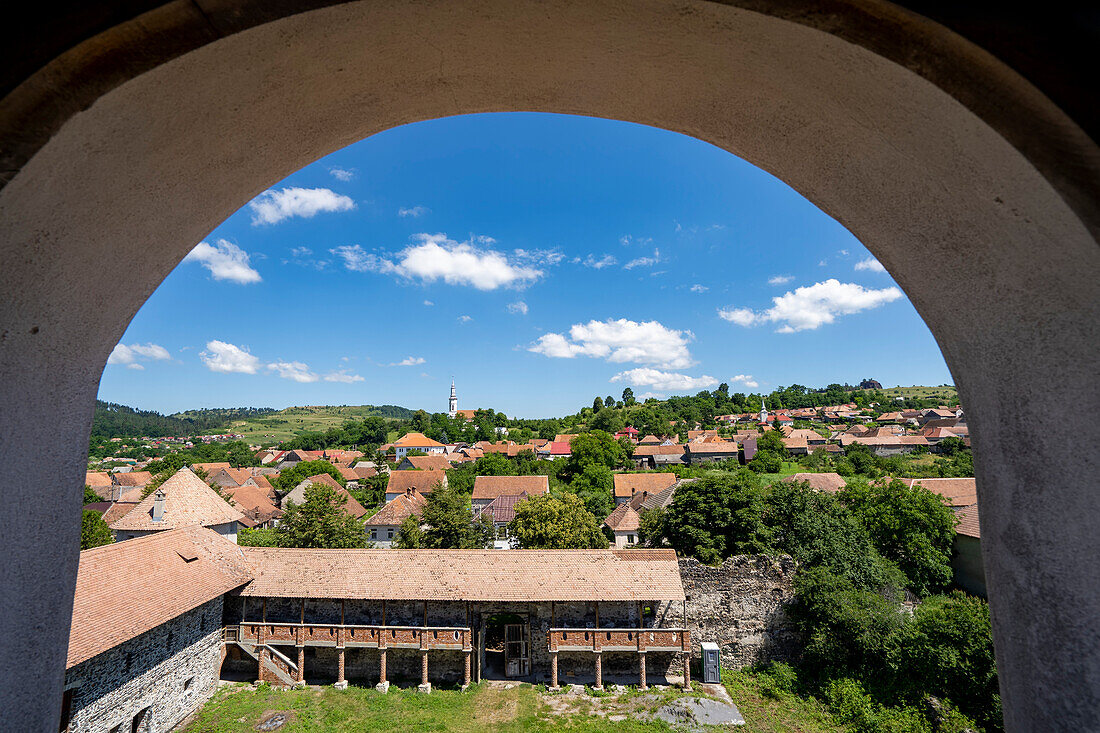 Blick auf die Stadt und die mittelalterliche Burg Cetatea Bethlen von Racos durch einen Torbogen; Racos, Siebenbürgen, Rumänien.