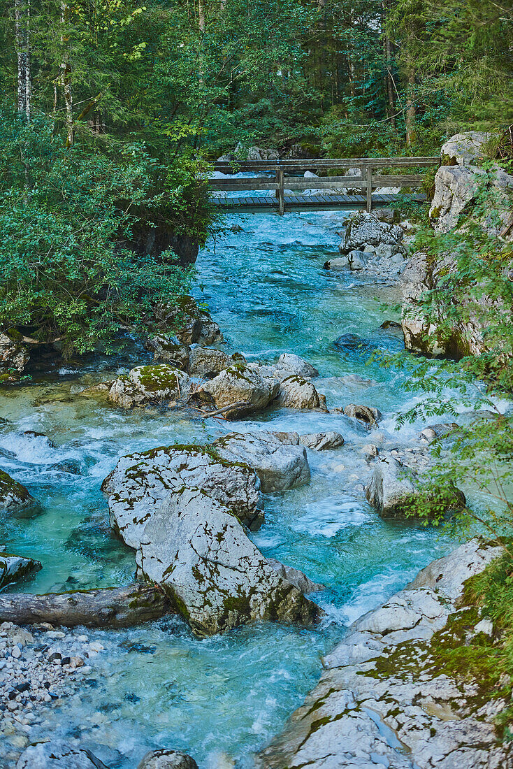 Fließende Ramsauer Ache mit türkisfarbenem Wasser und Steg in den Bayerischen Alpen; Berchtesgadener Land, Ramsau, Bayern, Deutschland.