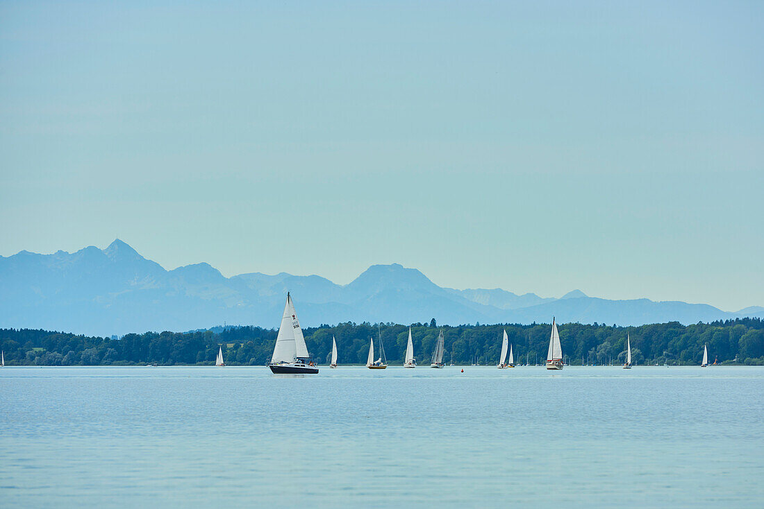 Sailing boats on Lake Chiemsee on a sunny day with a hazy blue sky; Bavaria, Germany