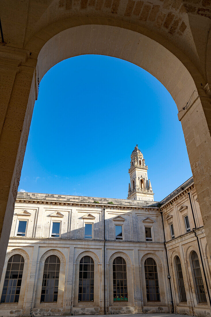 Bogengang mit Blick auf den Glockenturm der Kathedrale von Lecce auf der Piazza del Duomo im historischen Zentrum von Lecce; Lecce, Apulien, Italien.