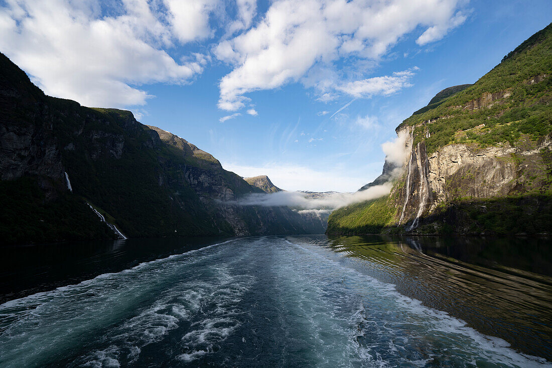 View of the Seven Sisters Waterfall with misty clouds hanging over the waterway while sailing through the 15 km long Geirangerfjord in Sunnmore; Geirangerfjord, Stranda, Norway