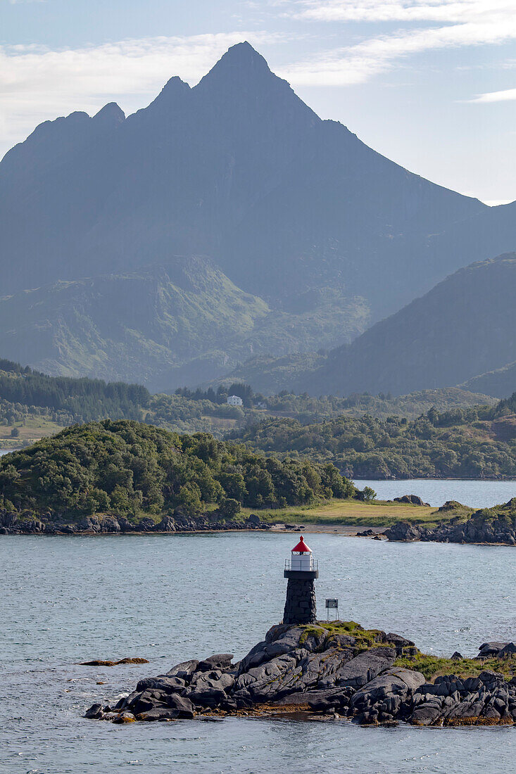 Leuchtturm von Buksnes in der abgelegenen Siedlung Gravdal auf der Insel Vestvagoya mit schemenhaften Berggipfeln in der Ferne auf den Lofoten; Lofoten, Nordland, Norwegen.