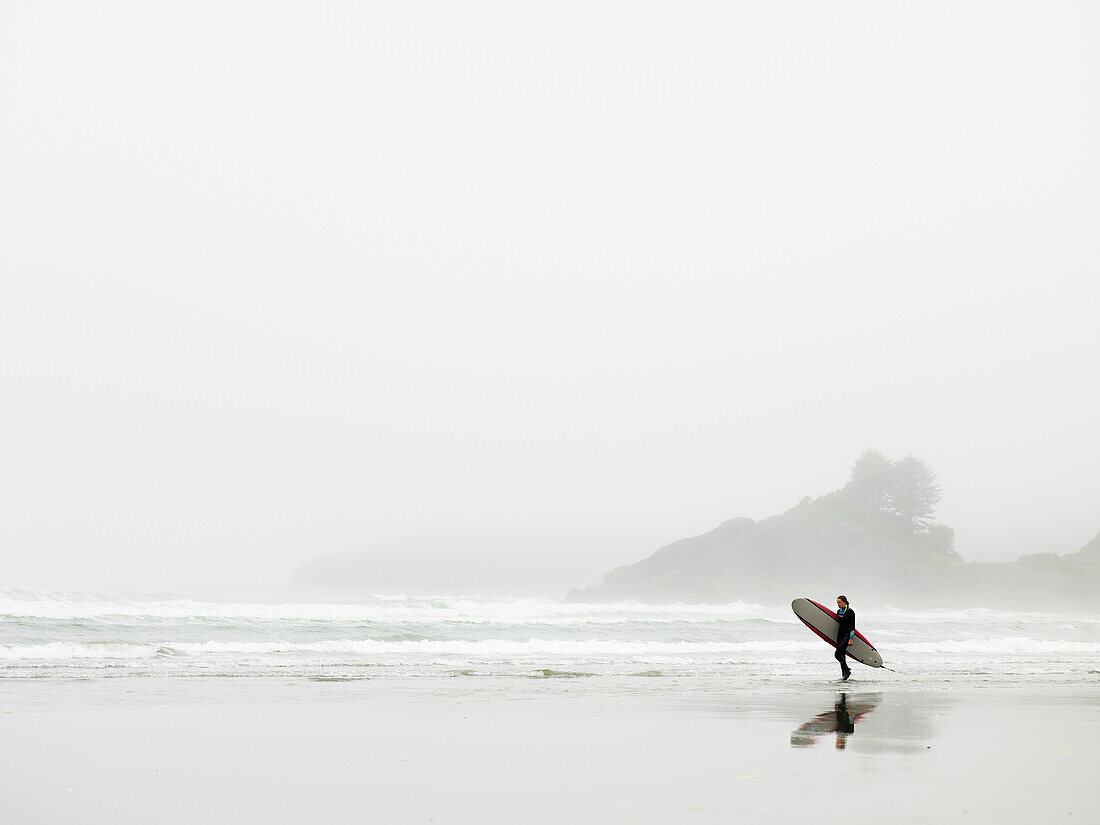 Surfer Walking On The Beach In Cox Bay; Tofino British Columbia Canada