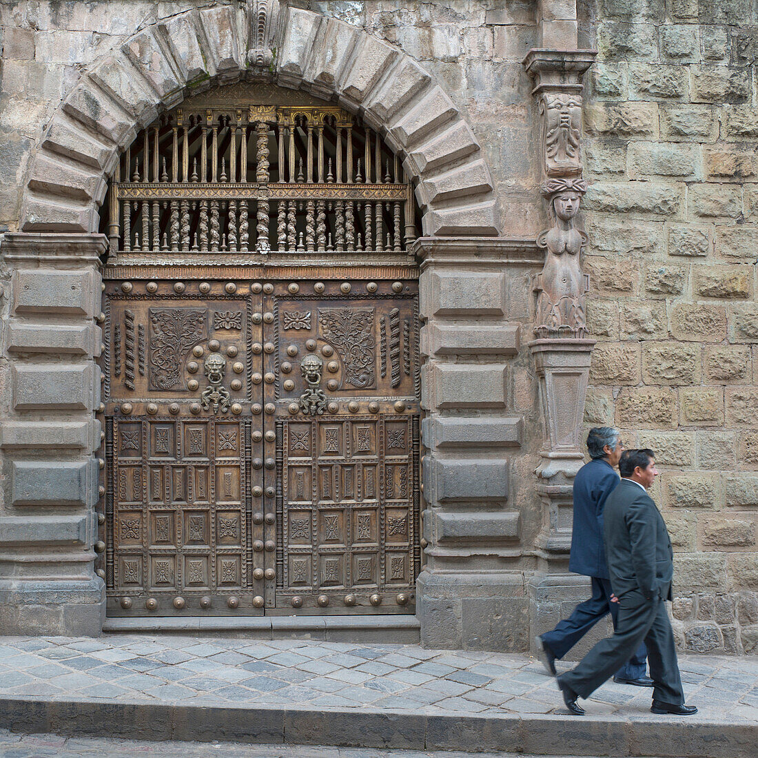 Two Men Walk By Ornate Doorway; Cusco Peru