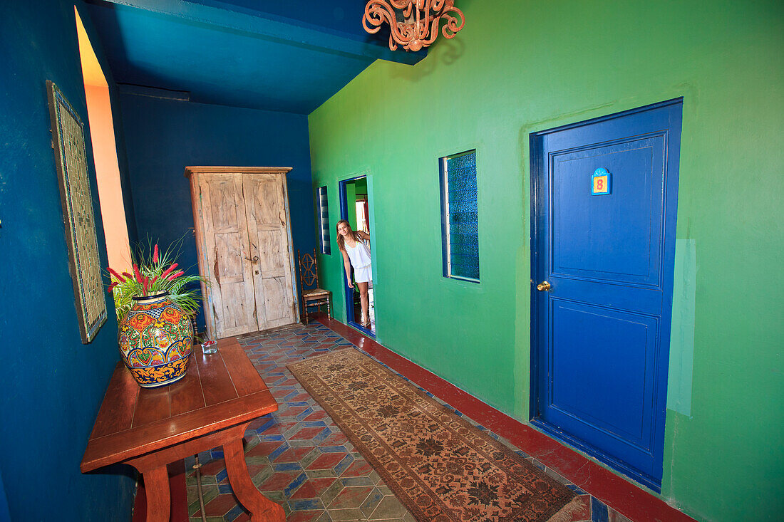 A Tourist Looks Out The Door Of Her Room Into The Hallway Of Hotel California; Todos Santos Baja California Sur Mexico