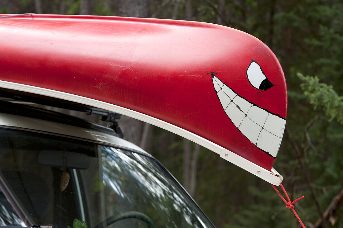 Ein Kanu mit einem gemalten Gesicht auf der Vorderseite ist an ein Fahrzeug geschnallt; Alberta Kanada