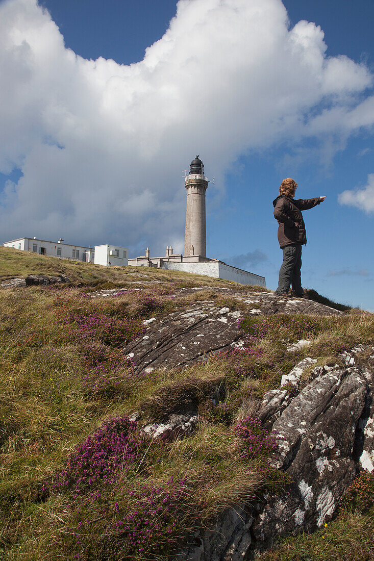 A Woman Points As She Stands In Front Of Ardnamurchan Lighthouse; Ardnamurchan Argyl Scotland