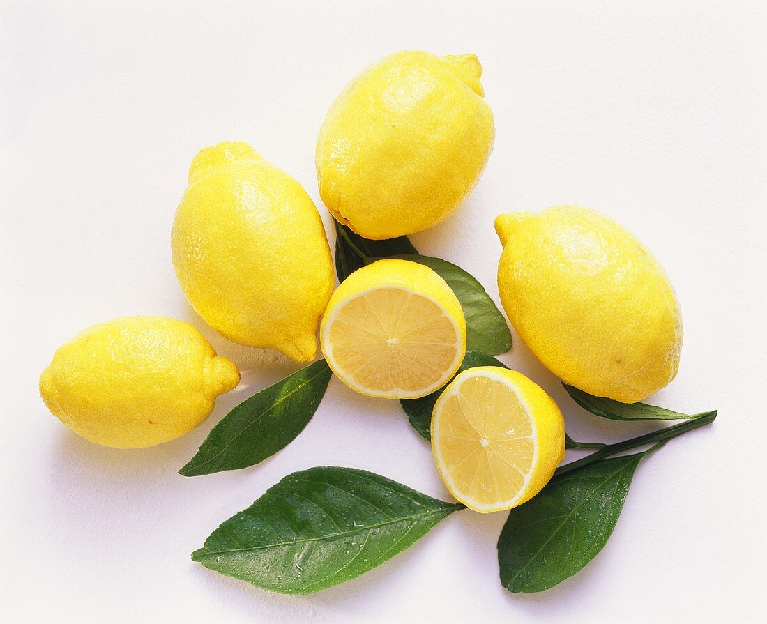 Vier ganze, eine halbierte Zitrone & Zitronenblätter