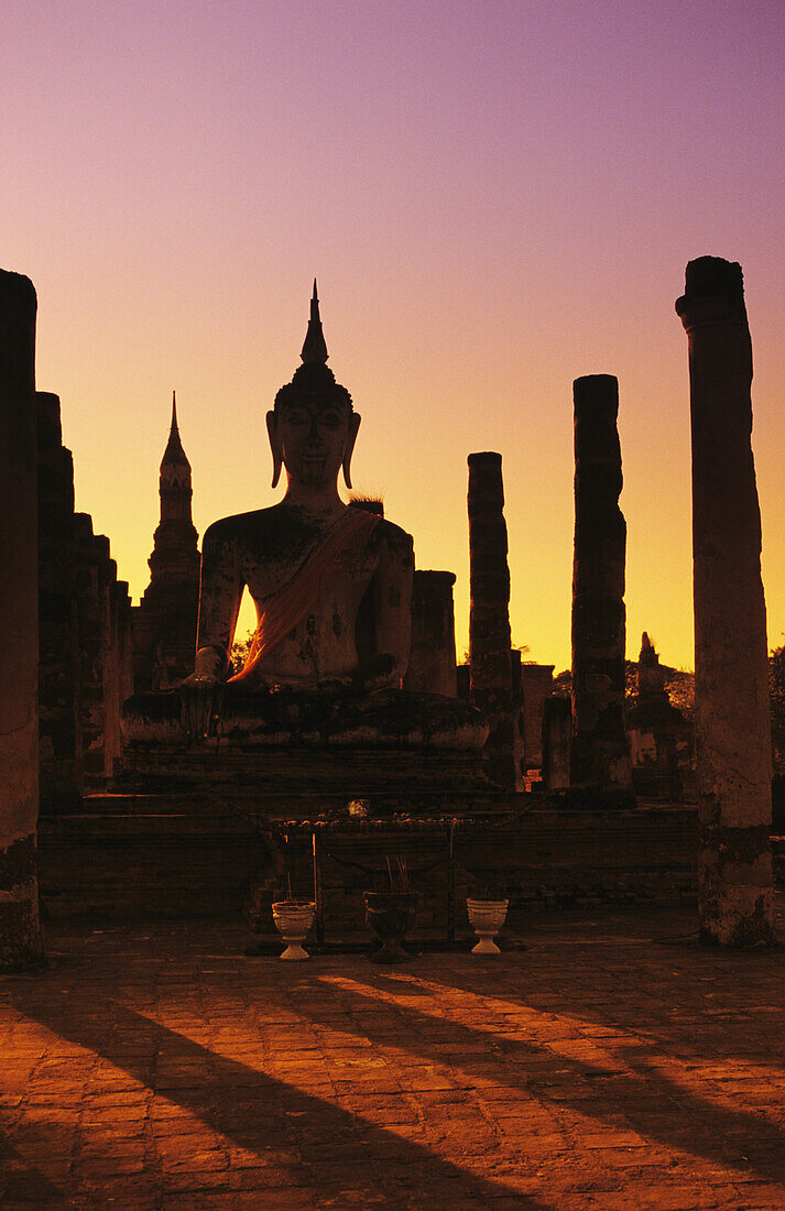 Thailand, Sukhothai, Wat Mahathat, Buddha And Pillars Backlit At Sunset