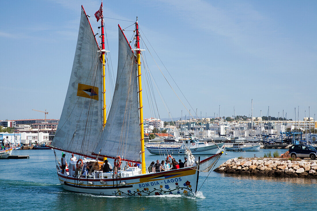 Ein Boot mit großen Segeln fährt durch den Hafen; Lagos Algarve Portugal