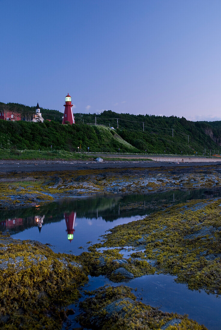 Red Lighthouse Reflecting In A Beach Pool; La Martre Quebec Canada