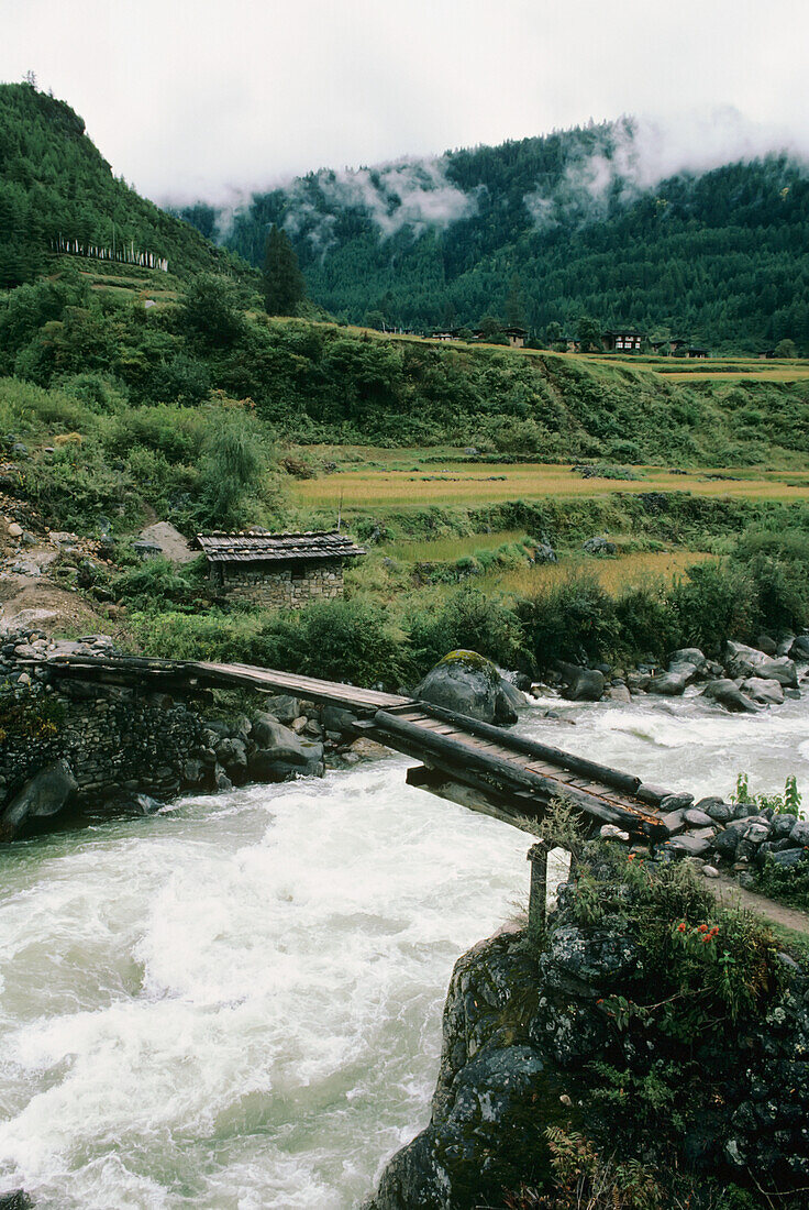 Bhutan, Wooden bridge over rushing river; Paro Valley
