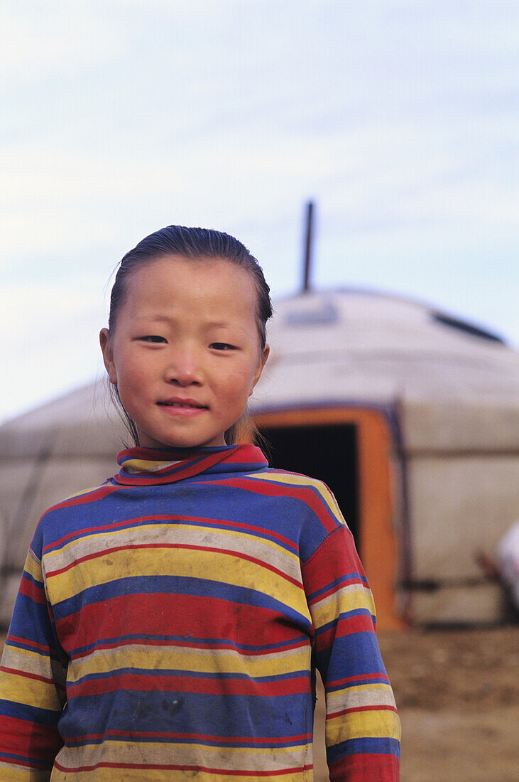 Mongolia, Young local girl standing in front of traditional nomadic home; Ger Ranch