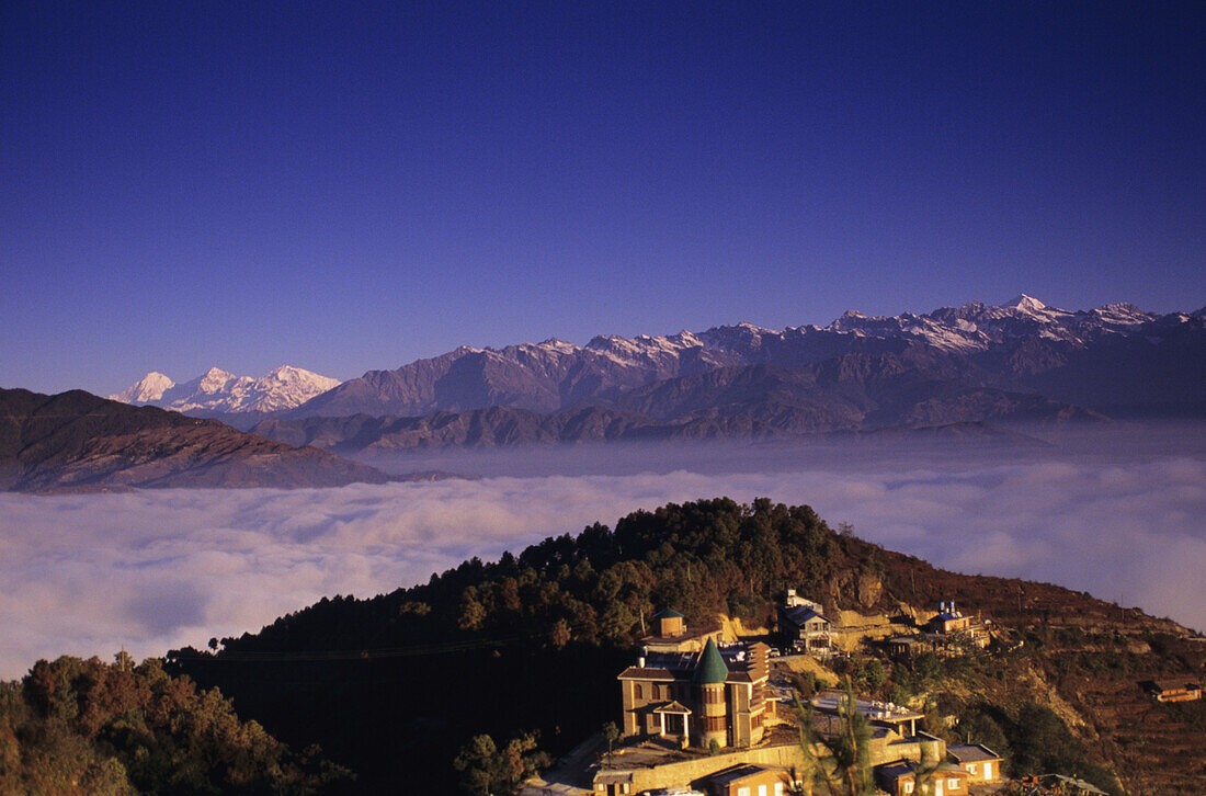 Nepal, Nagarkot, Überblick über die Niva Lodge am Berghang, Wolkenlinie und Himalaya-Gebirge im Hintergrund.
