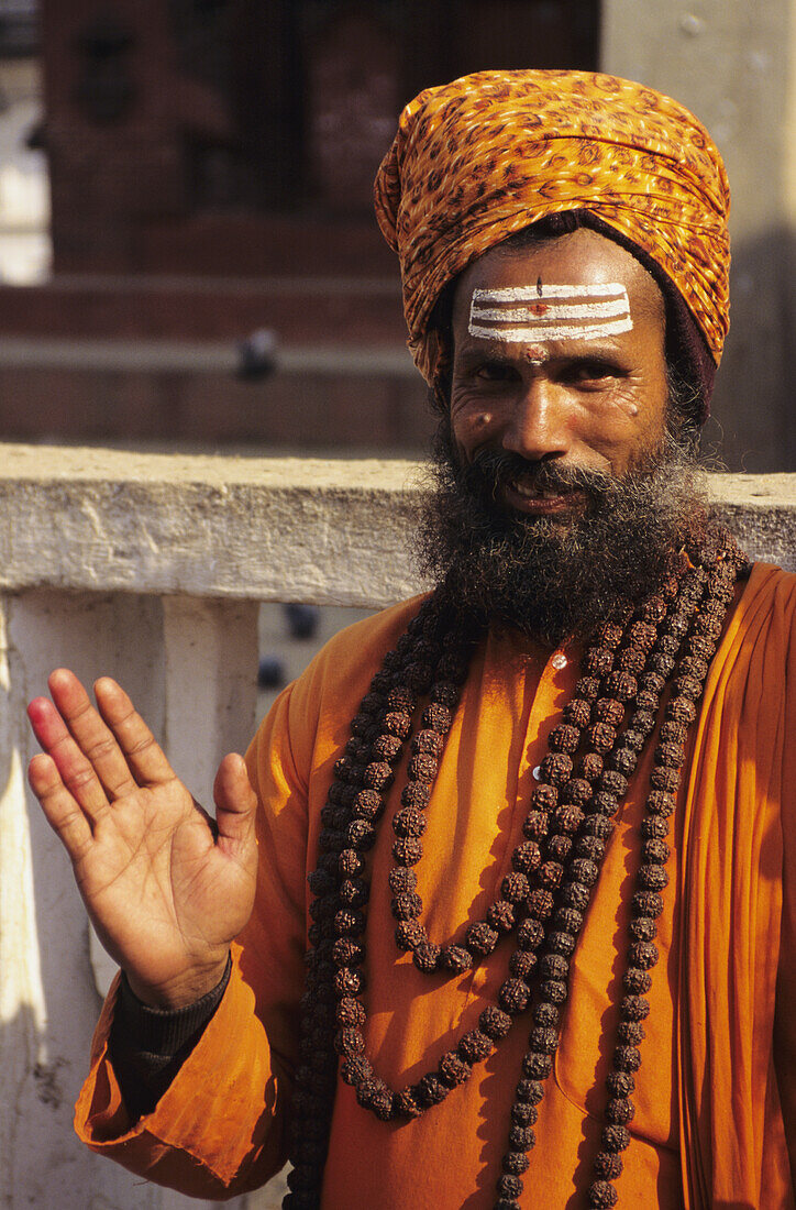 Nepal, Kathmandu Valley, Hindu Holy Man In Orange Robe And Turban, Smiling And Gesturing With Hand. Editorial Use Only.