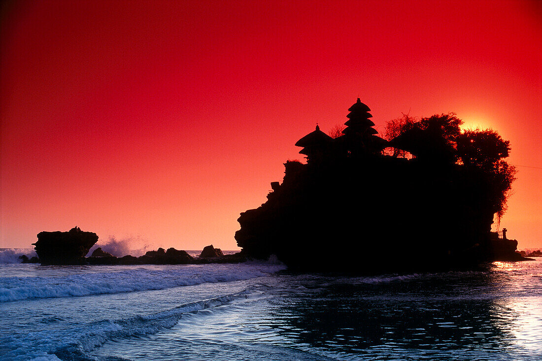 Indonesien, Bali, Tanah Lot im Schatten des dramatischen roten Abendhimmels