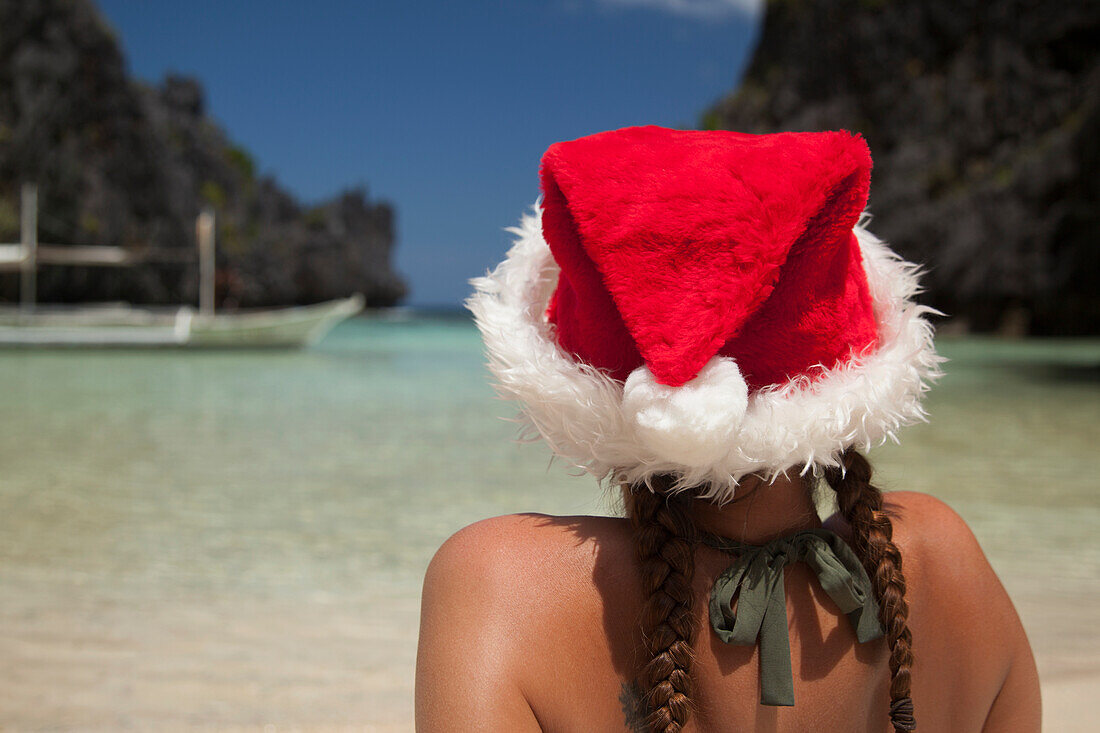 Eine Touristin trägt eine Weihnachtsmannmütze und einen Bikini auf der tropischen Matinloc-Insel in der Nähe von El Nido und Corong Corong; Bacuit-Archipel auf Palawan Philippinen