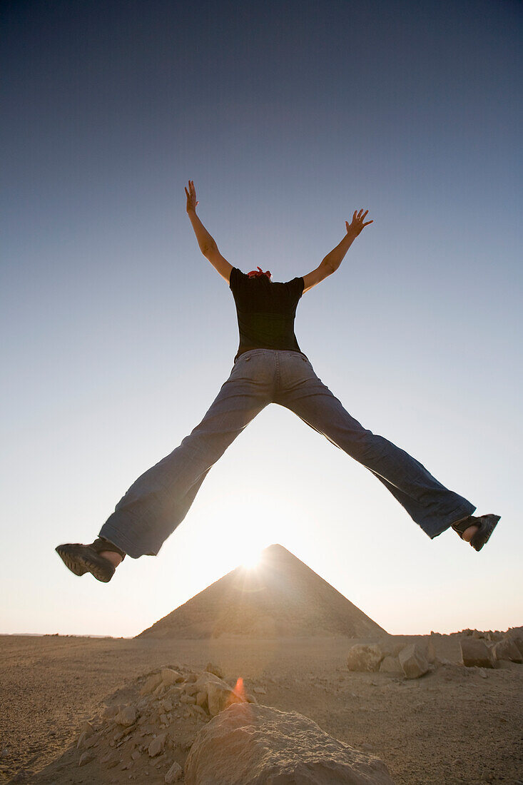 A Young Woman Tourist Jumps In The Air At The Red Pyramid; Dashur Egypt