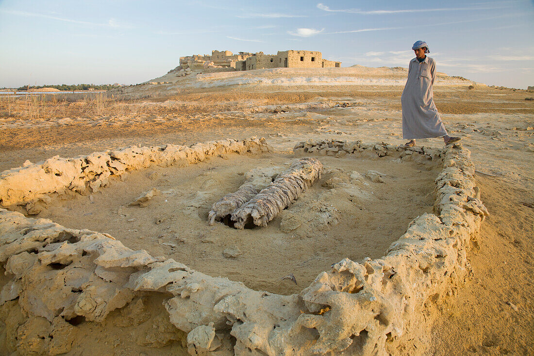 Ein einheimischer Mann aus Siwa betrachtet eine flache Grabstelle außerhalb der Stadt Siwa in der Oase Siwa; Siwa Ägypten