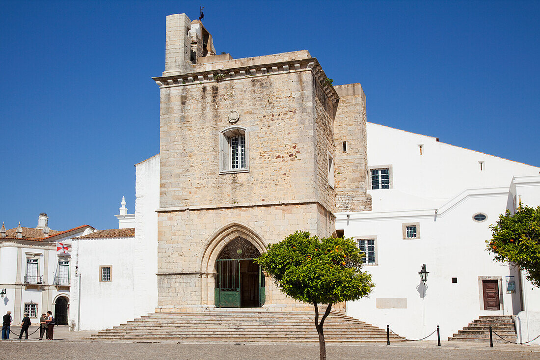 Touristen stehen vor einem Gebäude mit einem Glockenturm; Faro Algarve Portugal