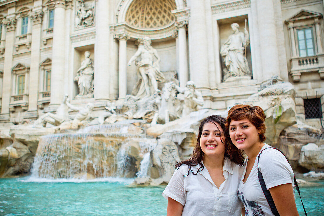 Zwei Freunde posieren vor dem Trevi-Brunnen; Rom, Italien