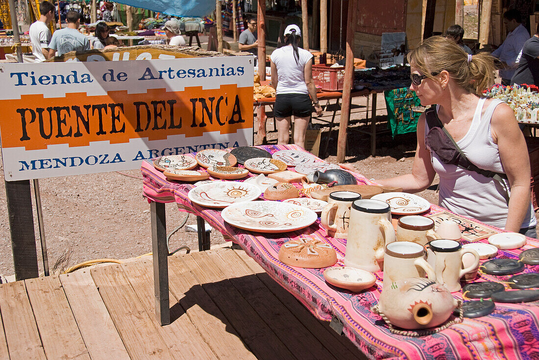 Weibliche Touristin begutachtet einheimische Kunst auf einem Markttisch in den Anden; Mendoza Argentinien