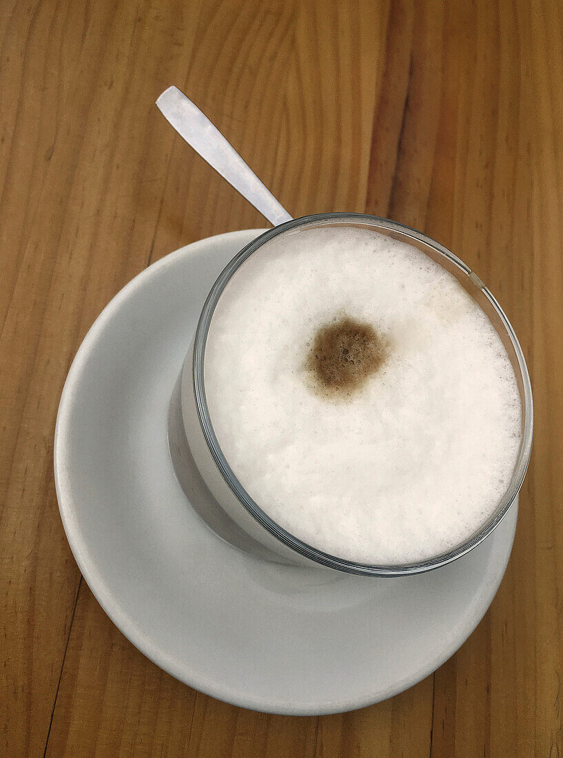 Blick von oben auf einen schaumigen Cappuccino auf einem Holztisch
