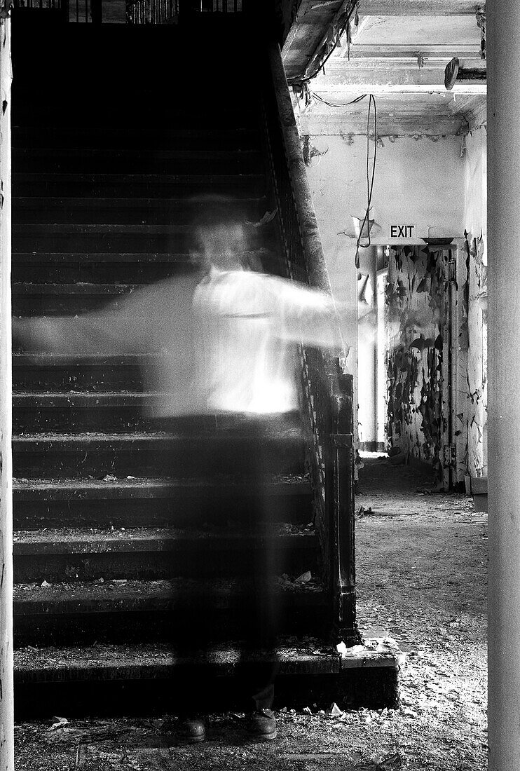 Transparenter Mann mit ausgestreckten Armen steht auf der Treppe eines verlassenen Gebäudes