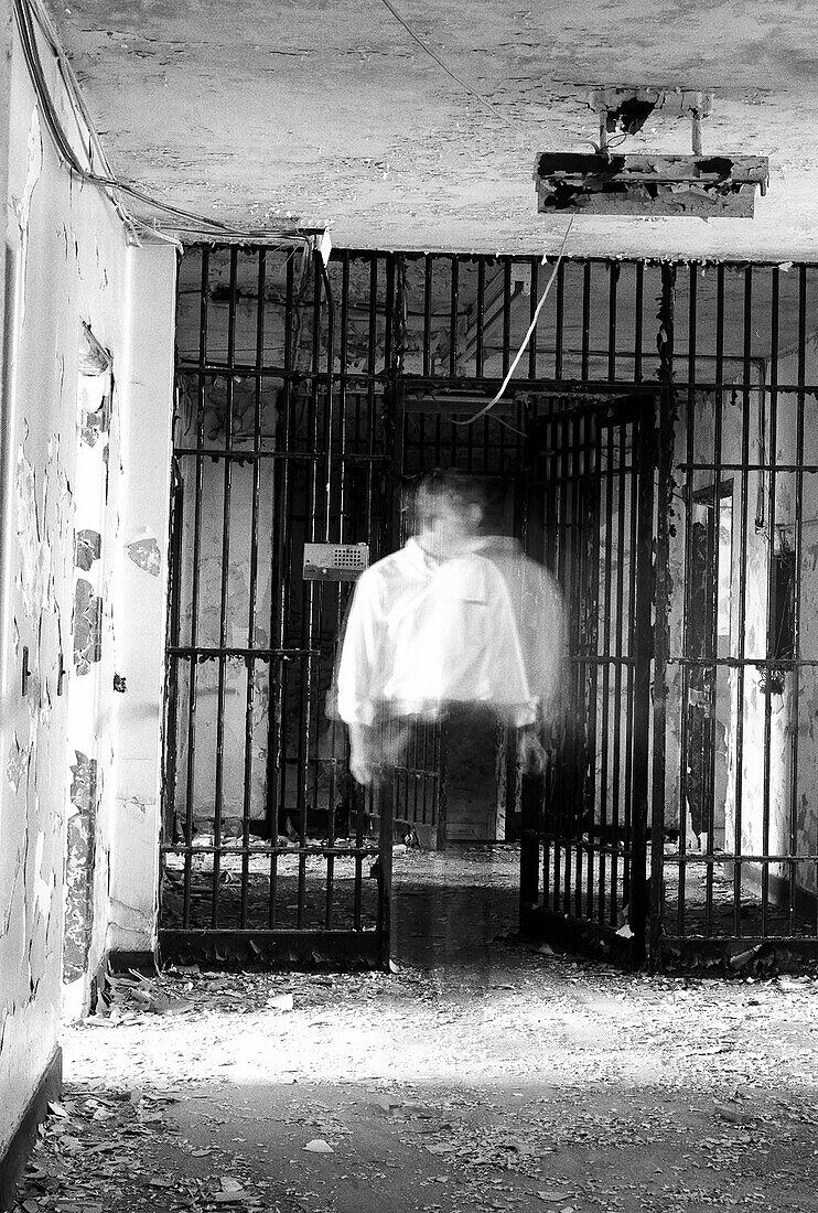Geisterhafter Mann steht in der Nähe der Gefängniszelle des verlassenen Gebäudes