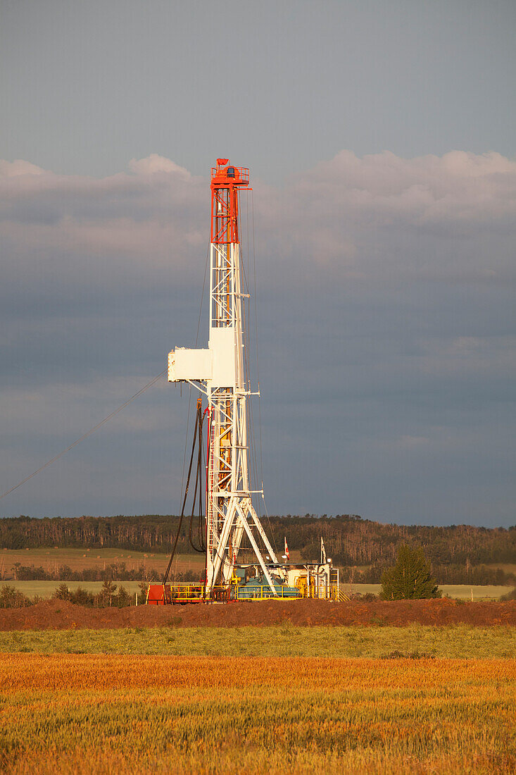 Bohrinsel in einem Feld bei Sonnenaufgang dramatisch beleuchtet; Alberta Kanada