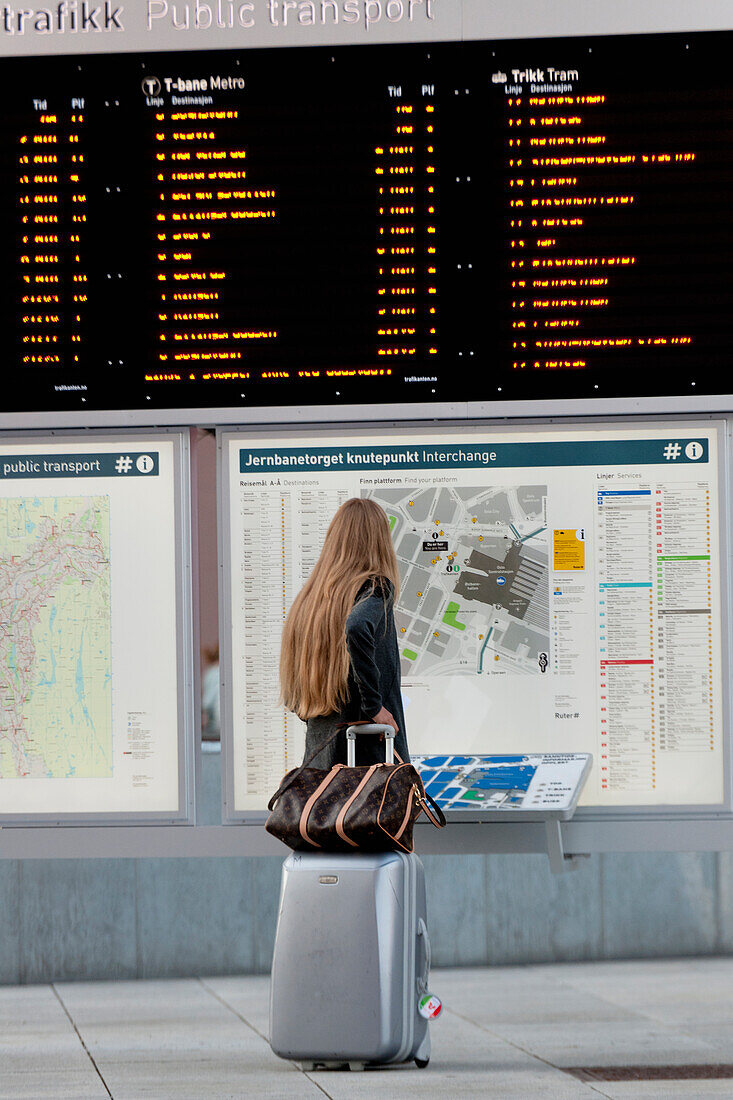 Eine Frau steht mit ihrem Gepäck und schaut auf die Karte der öffentlichen Verkehrsmittel; Oslo Norwegen