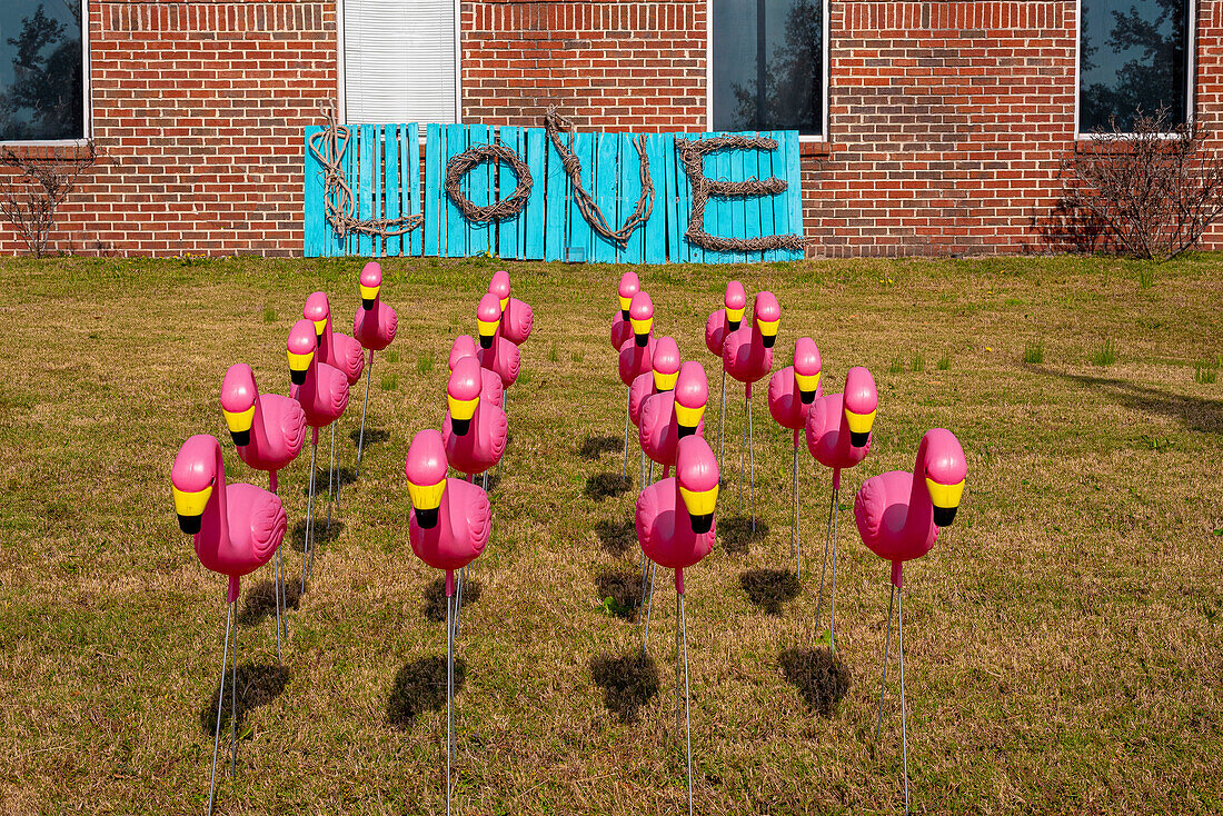 Rosa Flamingos aus Plastik mit Liebeszeichen im Hintergrund