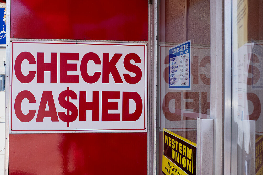 "Schecks eingelöst"-Schild an der Wand eines Finanzdienstleistungsgeschäfts
