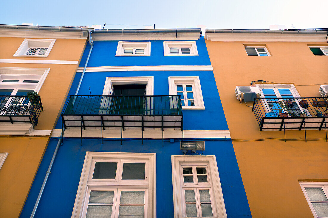 Niedriger Blickwinkel auf bunte Gebäudefassaden mit verglasten Fenstern und kleinen Balkonen, Valencia, Spanien