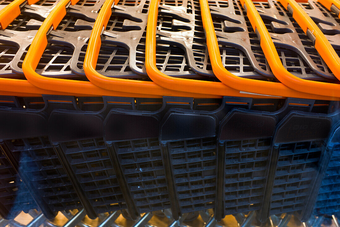 Detail einer Reihe von Einkaufswagen mit orangefarbenen Griffen