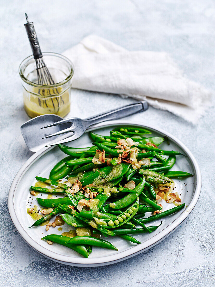 Grüne Bohnen und Erbsen mit Knoblauch und Pinienkernen