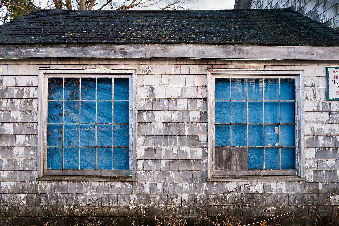 Dilapidated Wood Shingle building with Windows covered with Blue Tarp