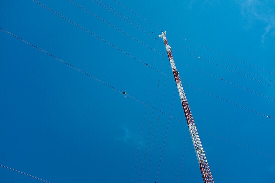 Niedriger Winkel des Fernmeldeturms mit Leitdrähten gegen den blauen Himmel