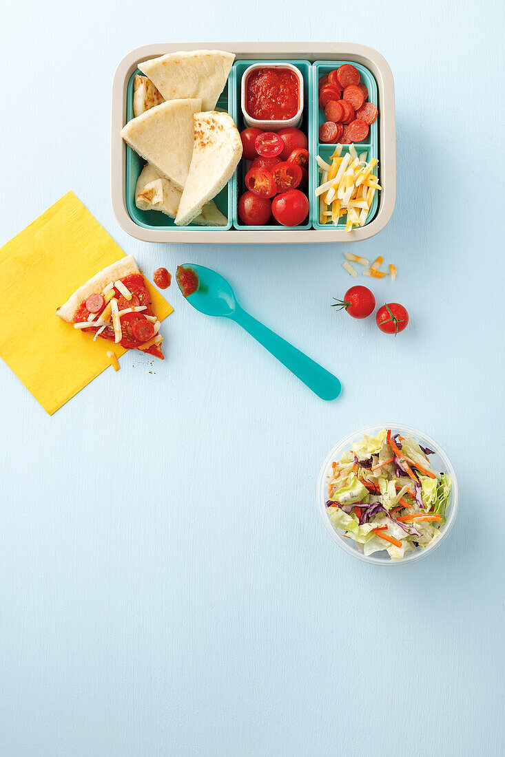 Lunchbox with pizza ingredients and salad