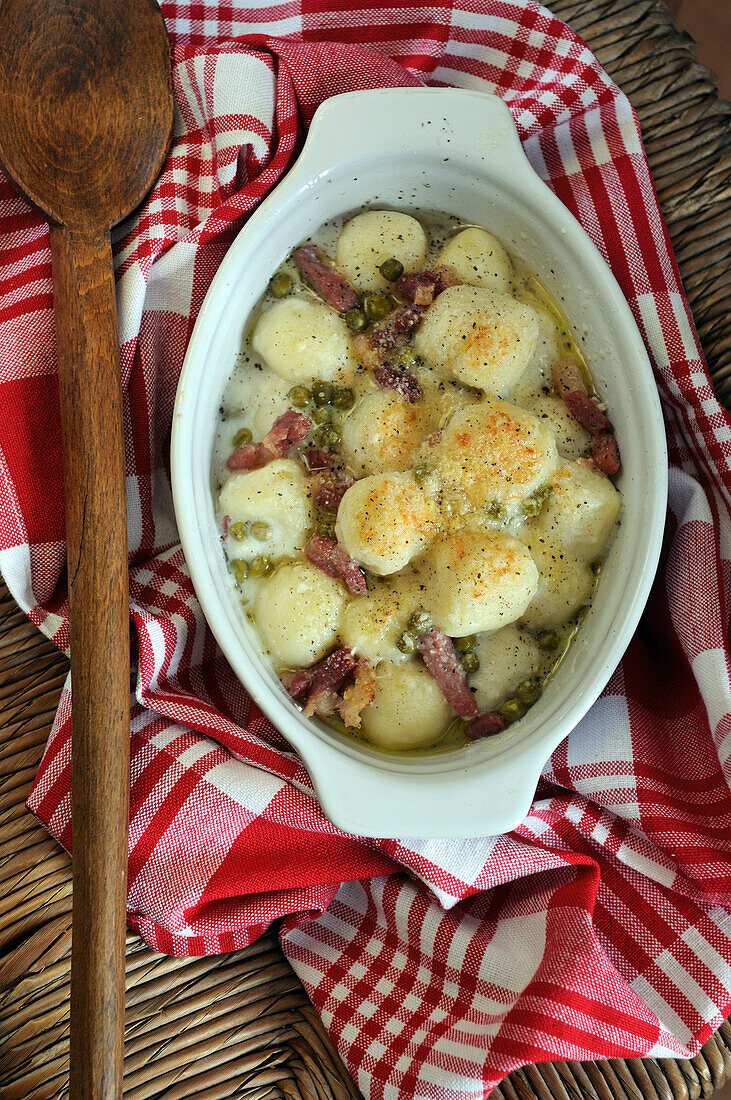 Homemade Italian gnocchi with cheese, peas and pancetta