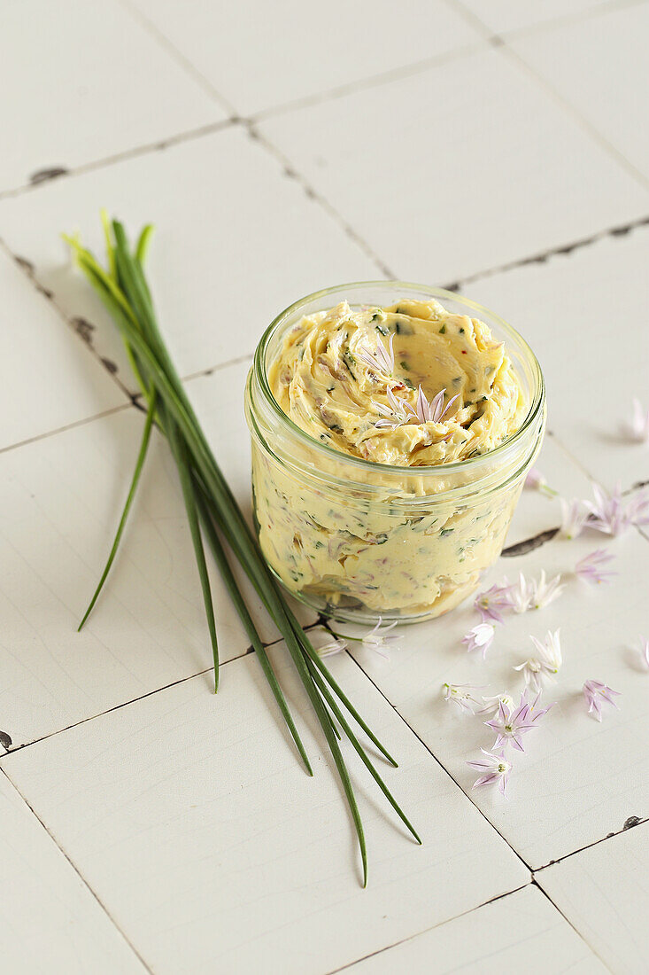 Aufgeschlagene Kräuterbutter mit Schnittlauchblüten und Knoblauch