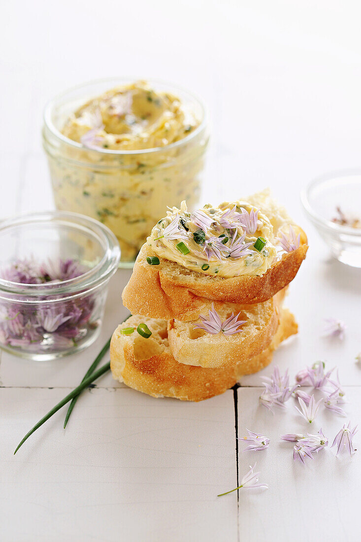 Aufgeschlagene Kräuterbutter mit Schnittlauchblüten und Knoblauch