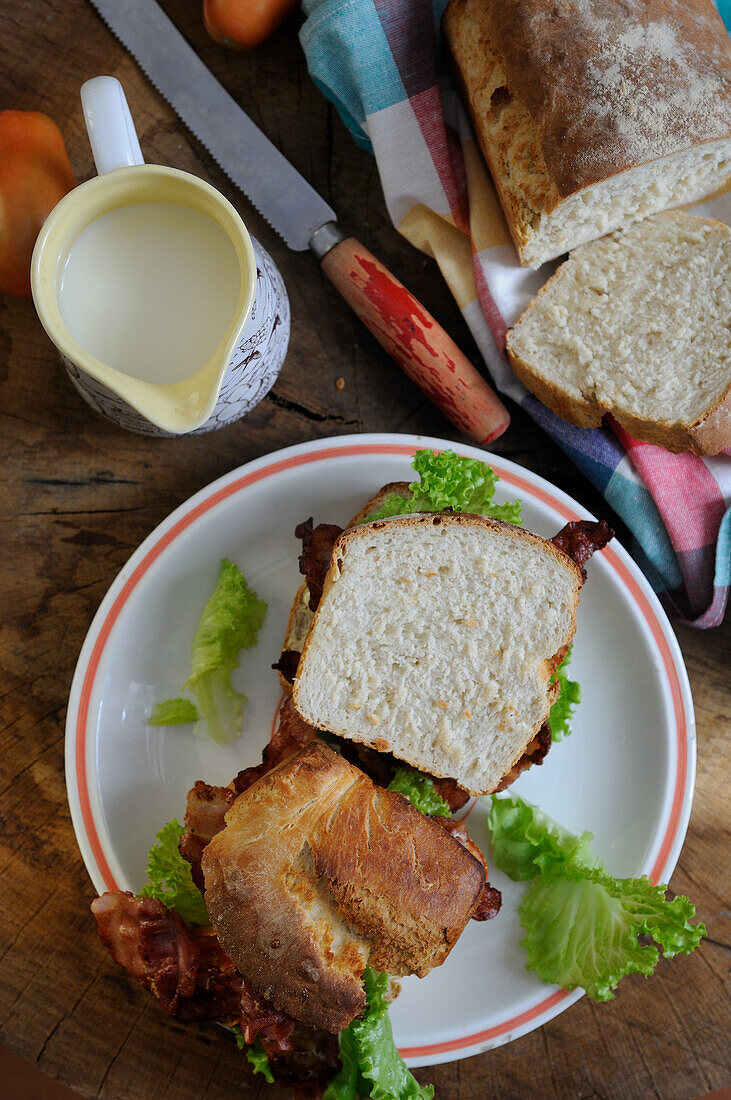 Sandwich aus hausgemachtem Brot mit Speck, Salat und Tomaten